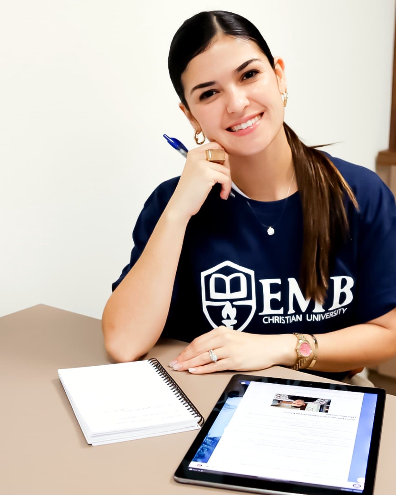 Aluna da EMB acompanhando uma aula no tablet, com caderno de anotações ao lado